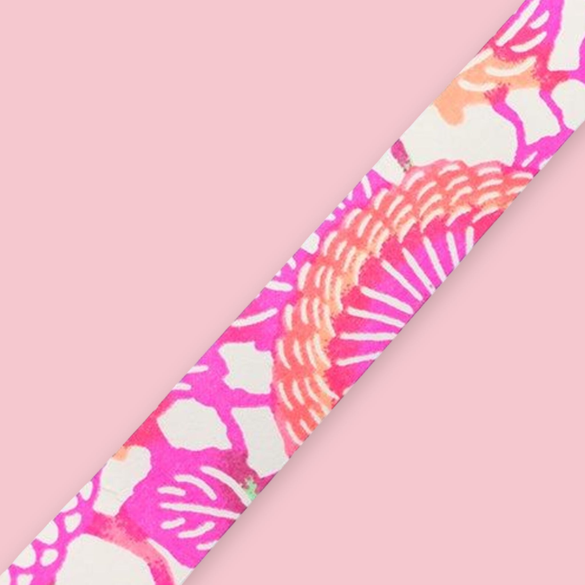 Strip of Shogado Yuzen Washi Tape in a neon floral pattern with magenta, orange, and white abstract sunburst motifs, against a pink background