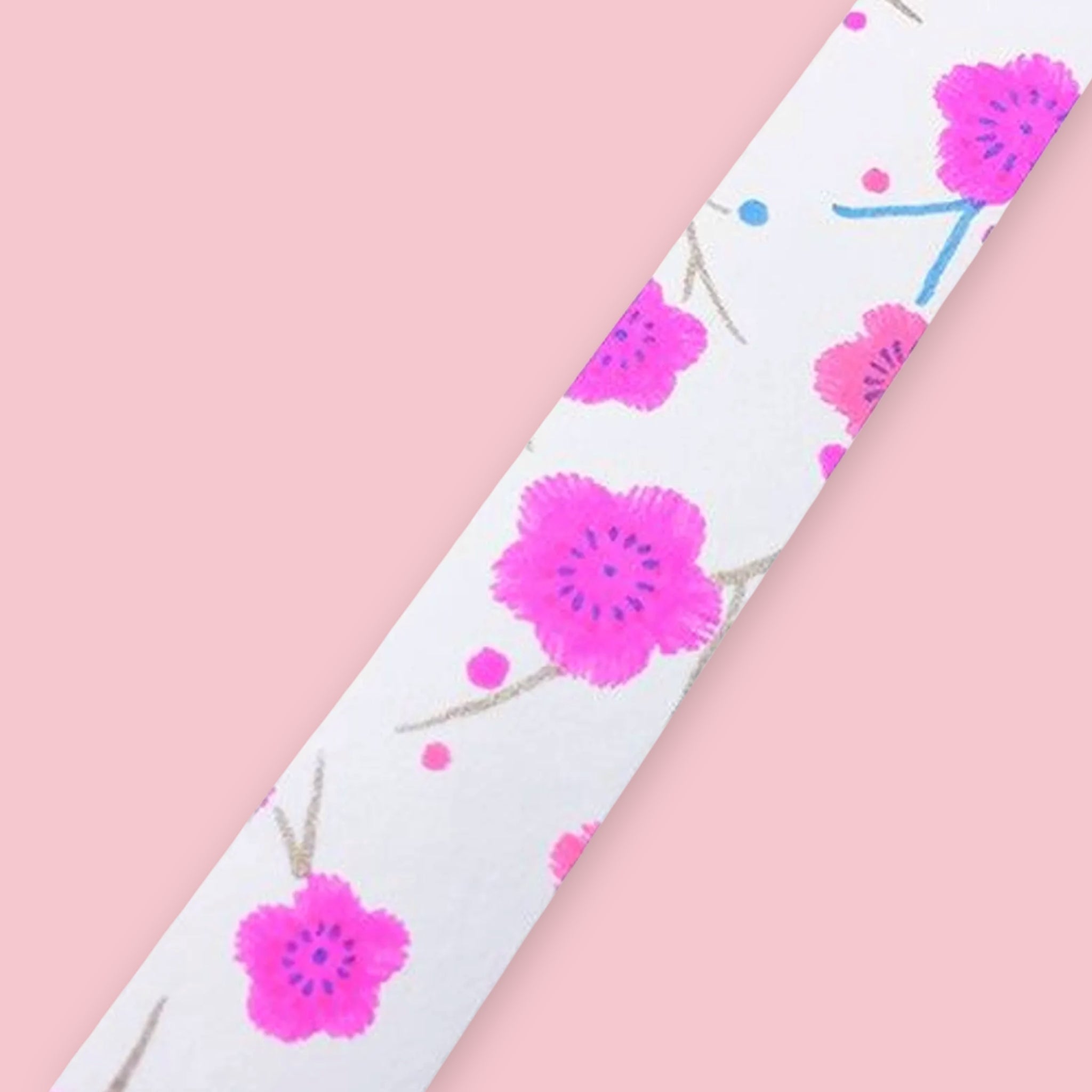 Strip of Shogado Yuzen Washi Tape in a neon floral pattern with pink cherry blossoms on a white background, against a pink background