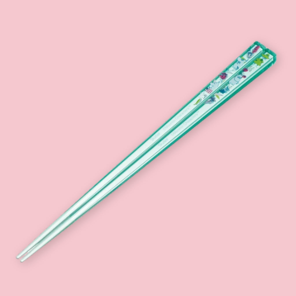 Transparent teal Moomin chopsticks decorated with small character illustrations on a pink background