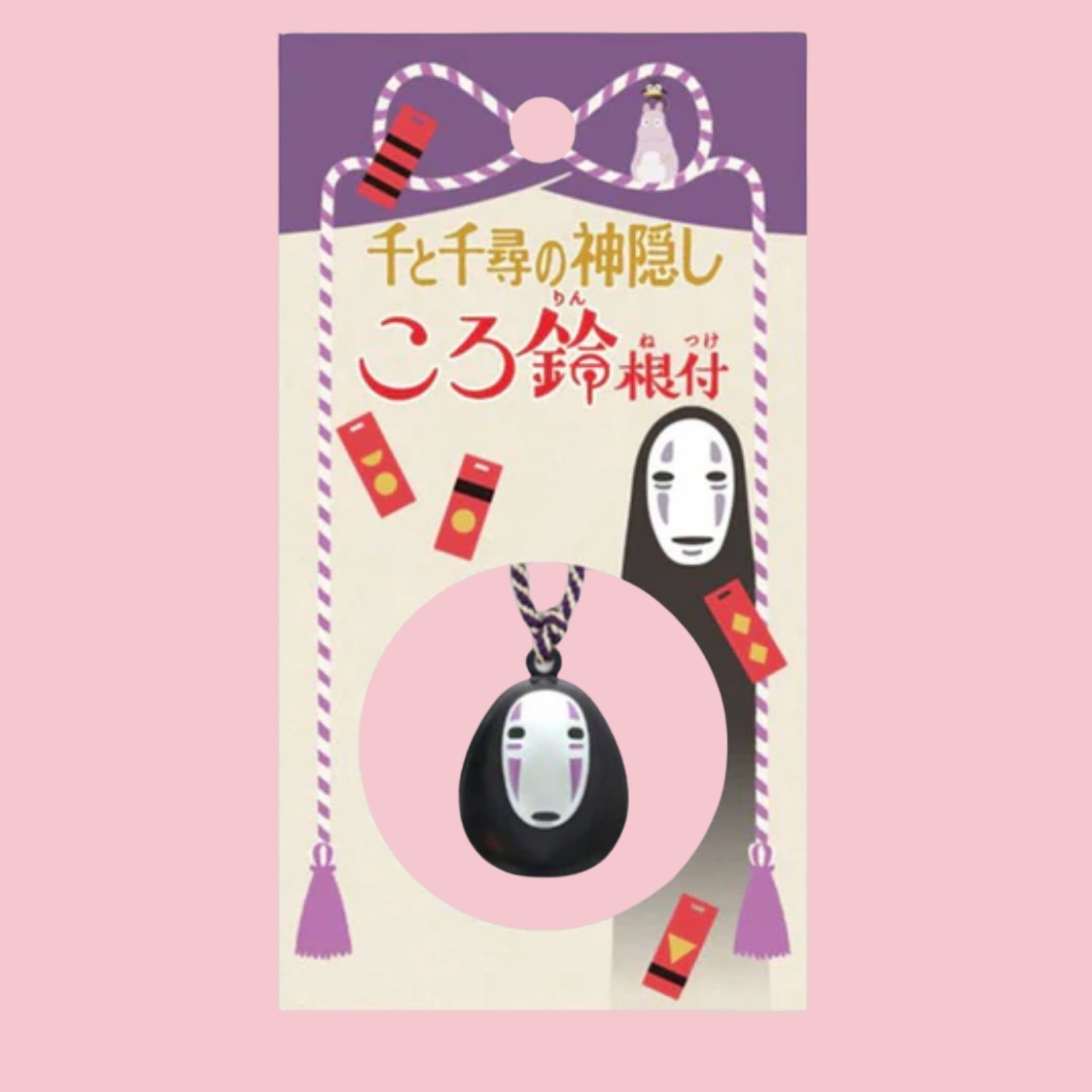 Original Japanese packaging card for the Spirited Away No-Face bell charm, featuring the No-Face illustration and Japanese title in gold and red text on a purple backdrop, with the black and white No-Face bell charm shown hanging on its purple and cream cord inside a circular pink window at the bottom of the card.
