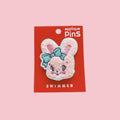 Pink fuzzy bunny face applique pin with a blue bow, attached to a red Swimmer card on a pink background.