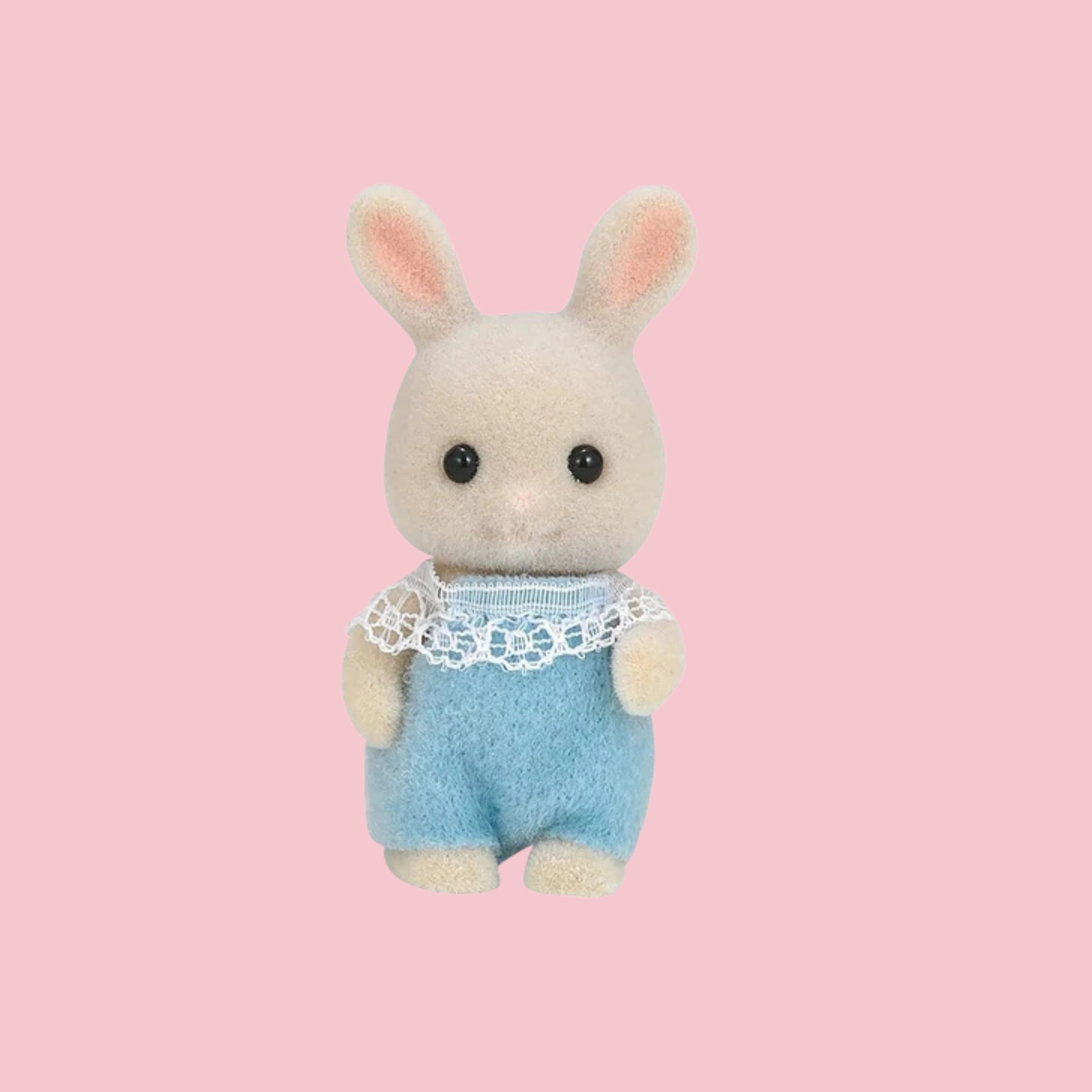 Sylvanian Families milk rabbit baby figure in green outfit, shown against a pink background.