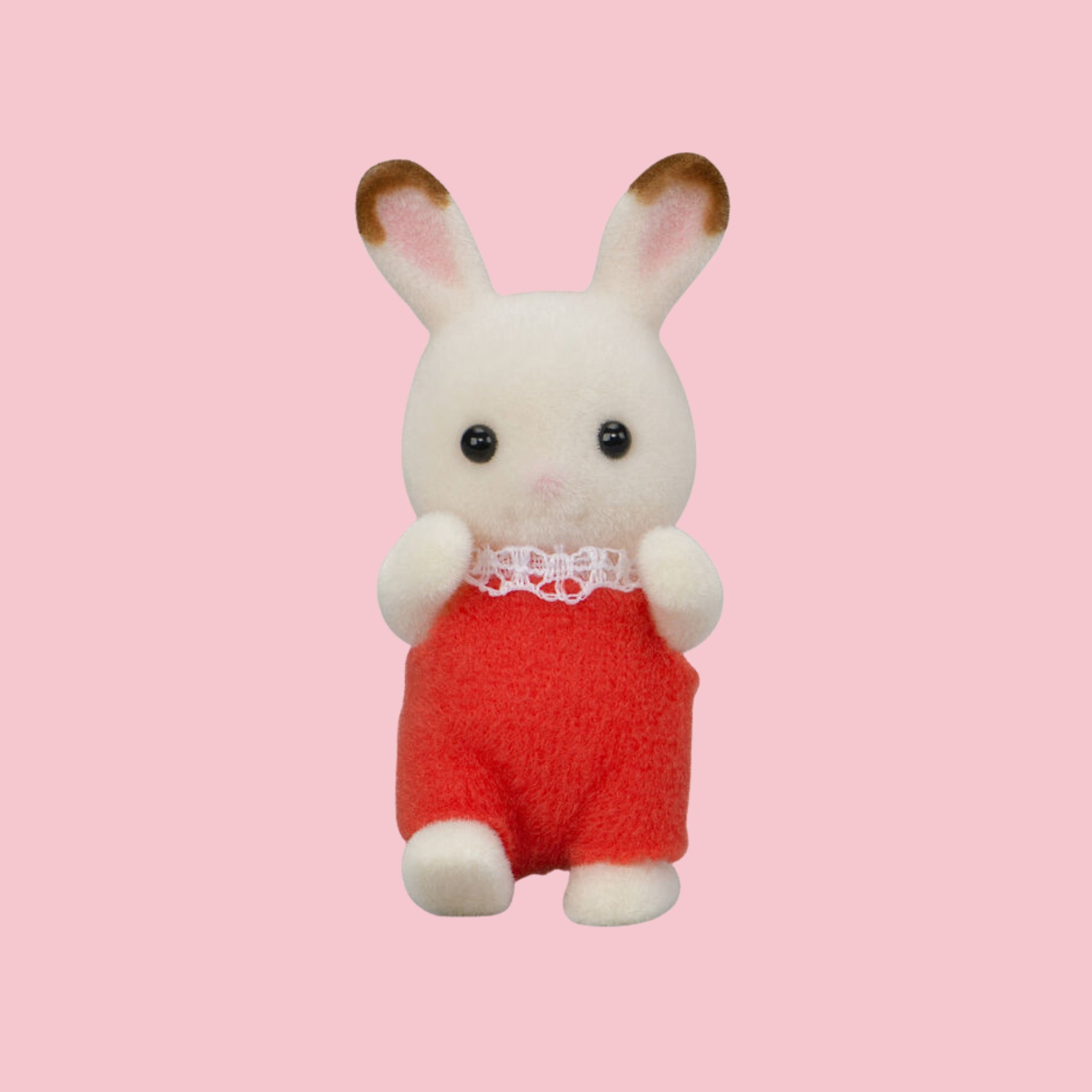 Sylvanian Families chocolate rabbit baby figure in green outfit, shown against a pink background.