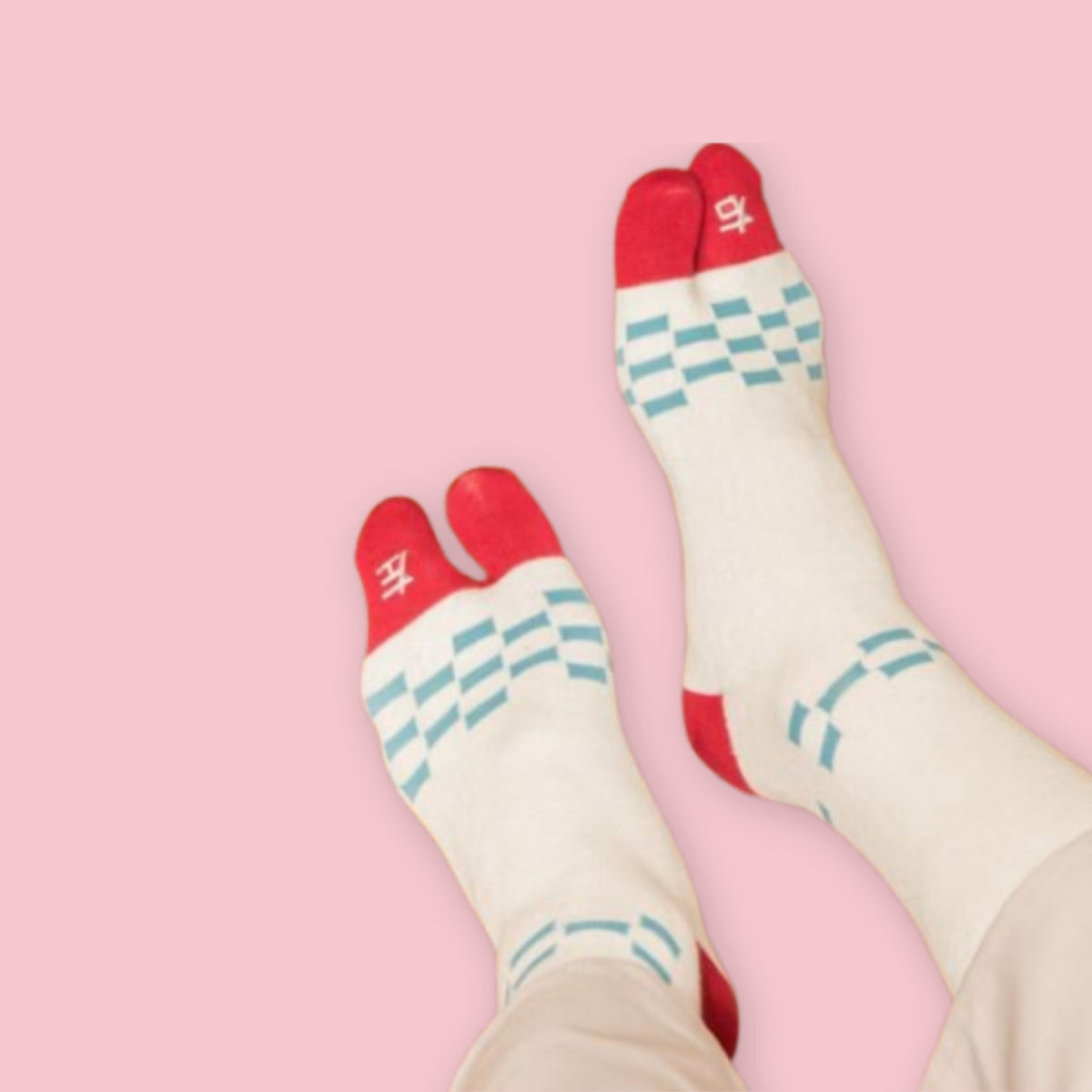 White Japanese tabi socks with red split toes and heels, turquoise checkerboard stripes, and a pink background.