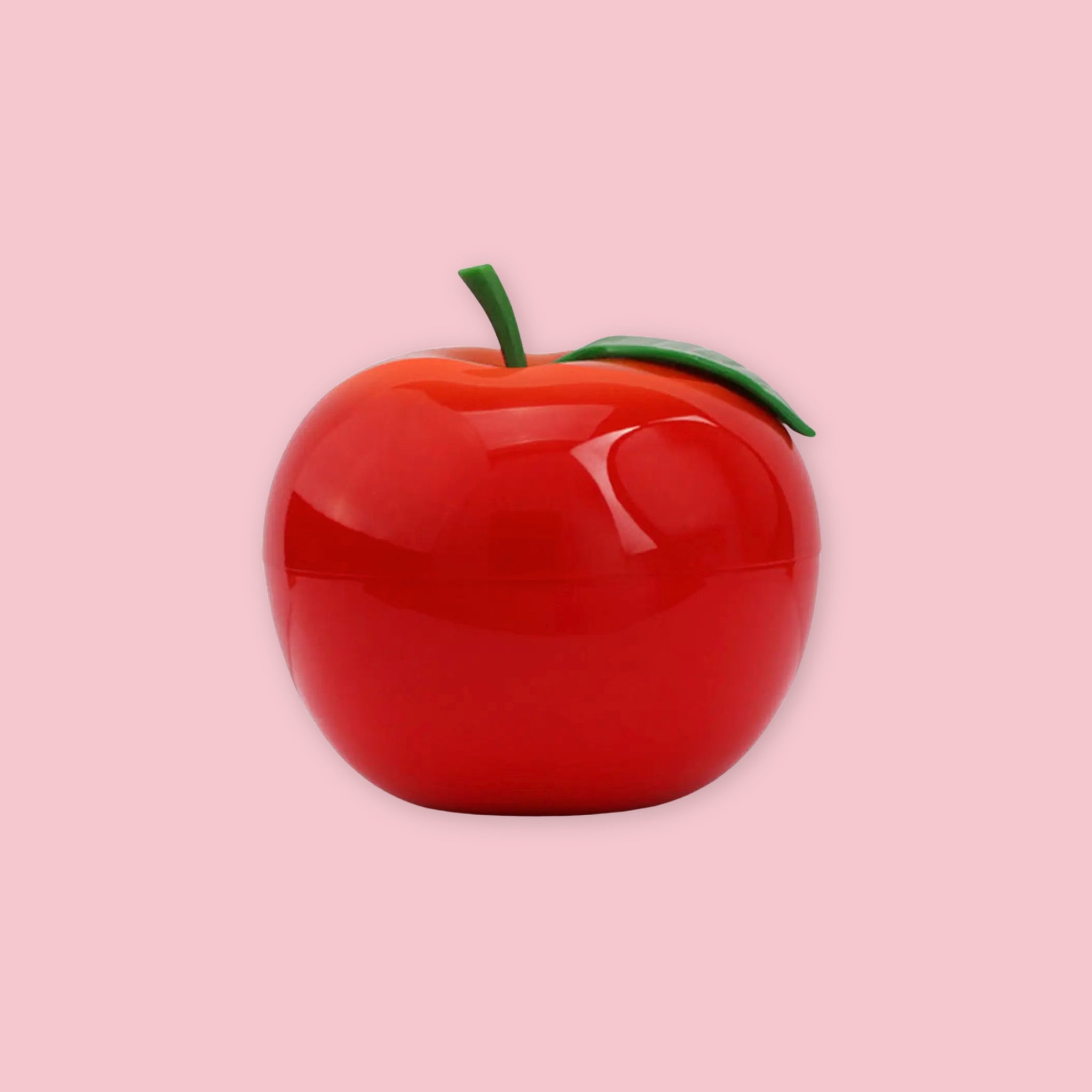 TonyMoly Red Apple Hand Cream in a glossy red apple-shaped container with a green stem and leaf, on a pink background.