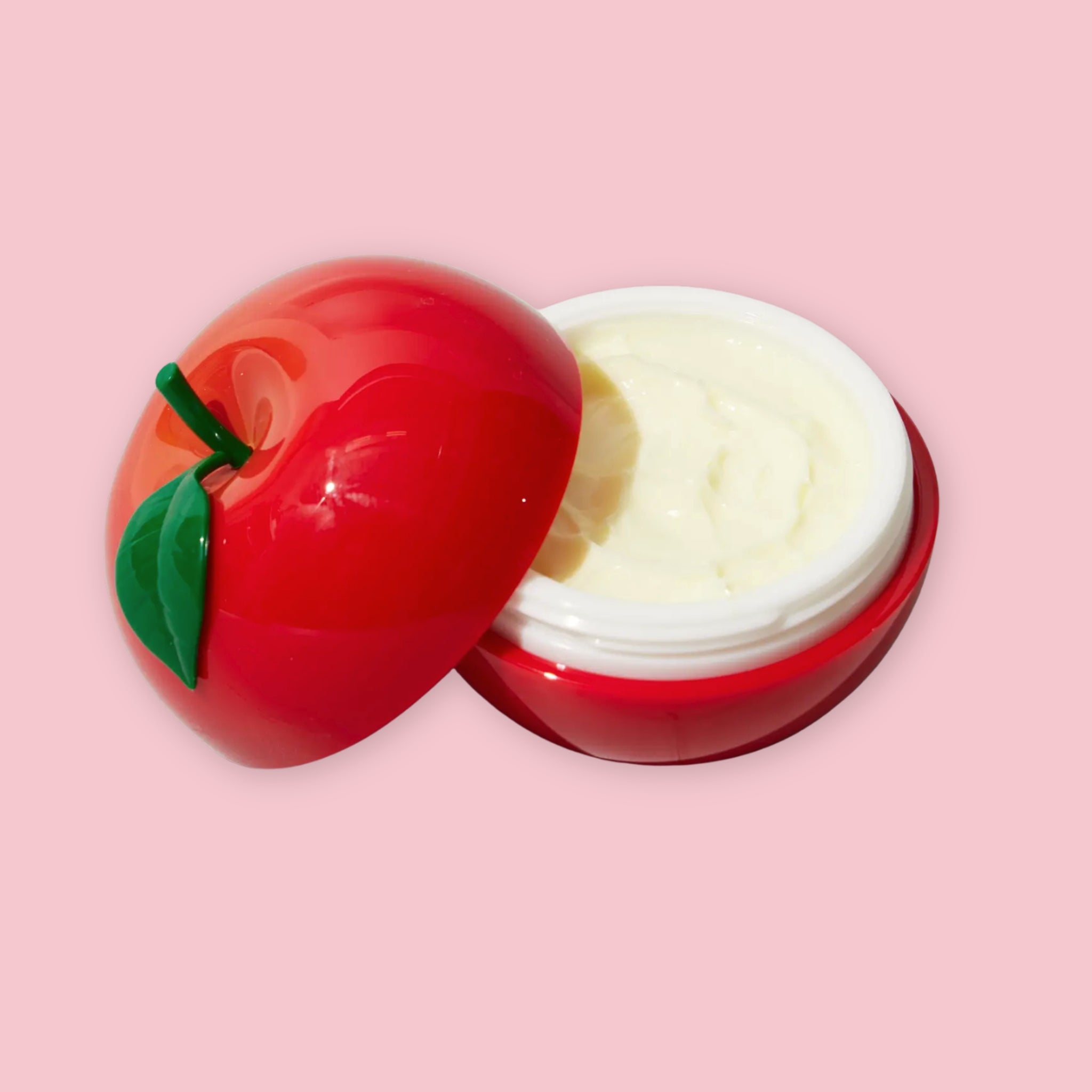 TonyMoly Red Apple Hand Cream open to show the cream inside, with the apple-shaped lid resting beside the jar, on a pink background.