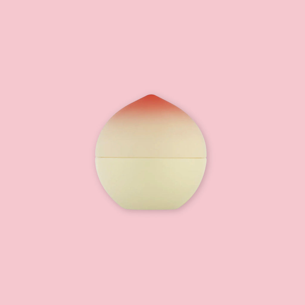 TonyMoly Peach Lip Balm in a peach-shaped container with a gradient red to cream finish, on a pink background.