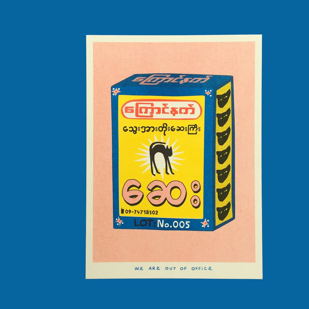 We Are Out of Office risograph art print featuring a colorful Burmese-style product box illustration with a black cat graphic, photographed against blue.