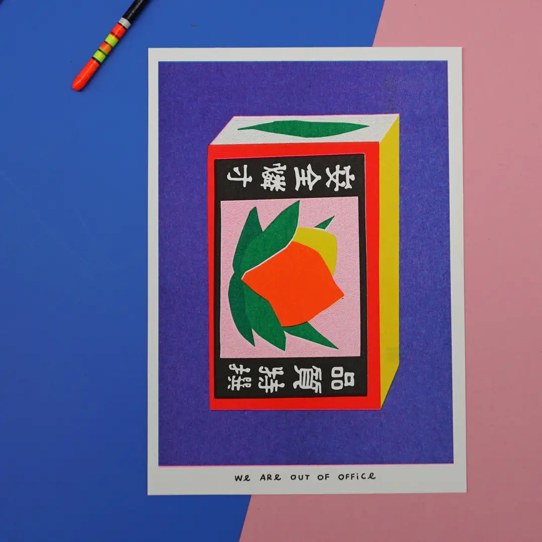 We Are Out of Office risograph art print featuring a colorful Japanese matchbox illustration, photographed on a blue and pink background with a small charm.