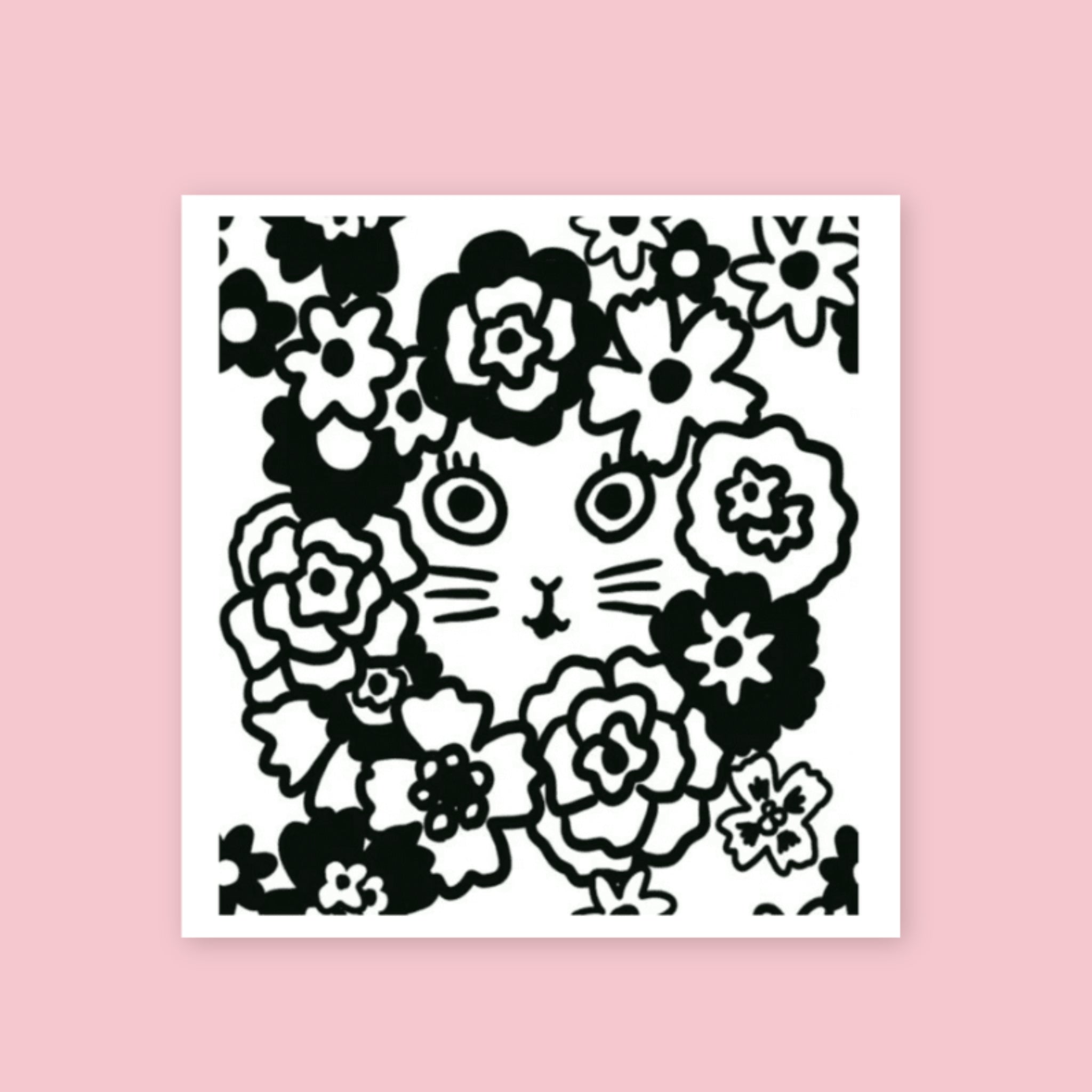 Yumi Kitagishi rubber stamp showing a cat face surrounded by a wreath of large flowers, printed in black ink on white paper, on a pink background.