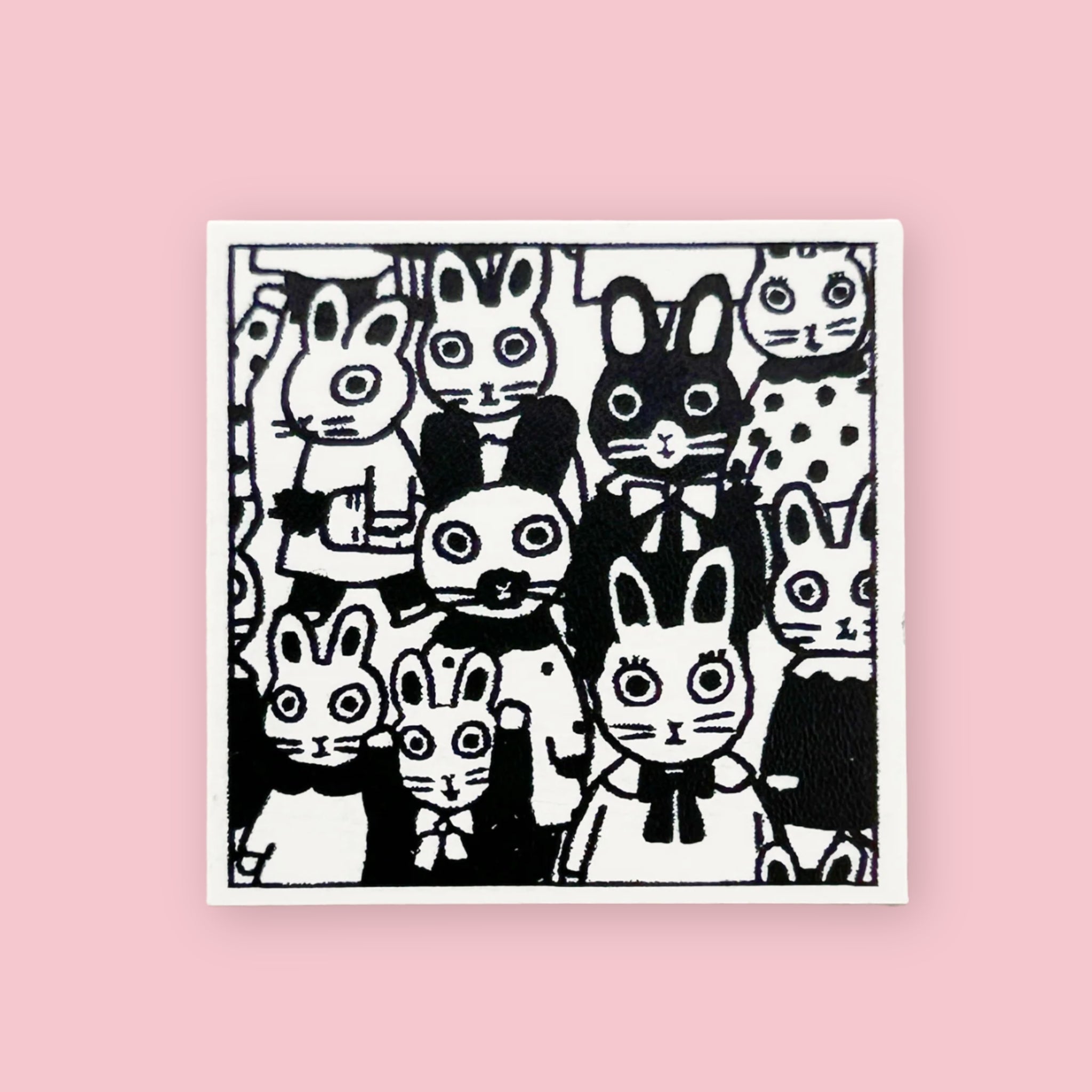 Yumi Kitagishi rubber stamp showing a crowd of wide-eyed rabbits in various sizes and poses, printed in black ink on white paper, on a pink background.